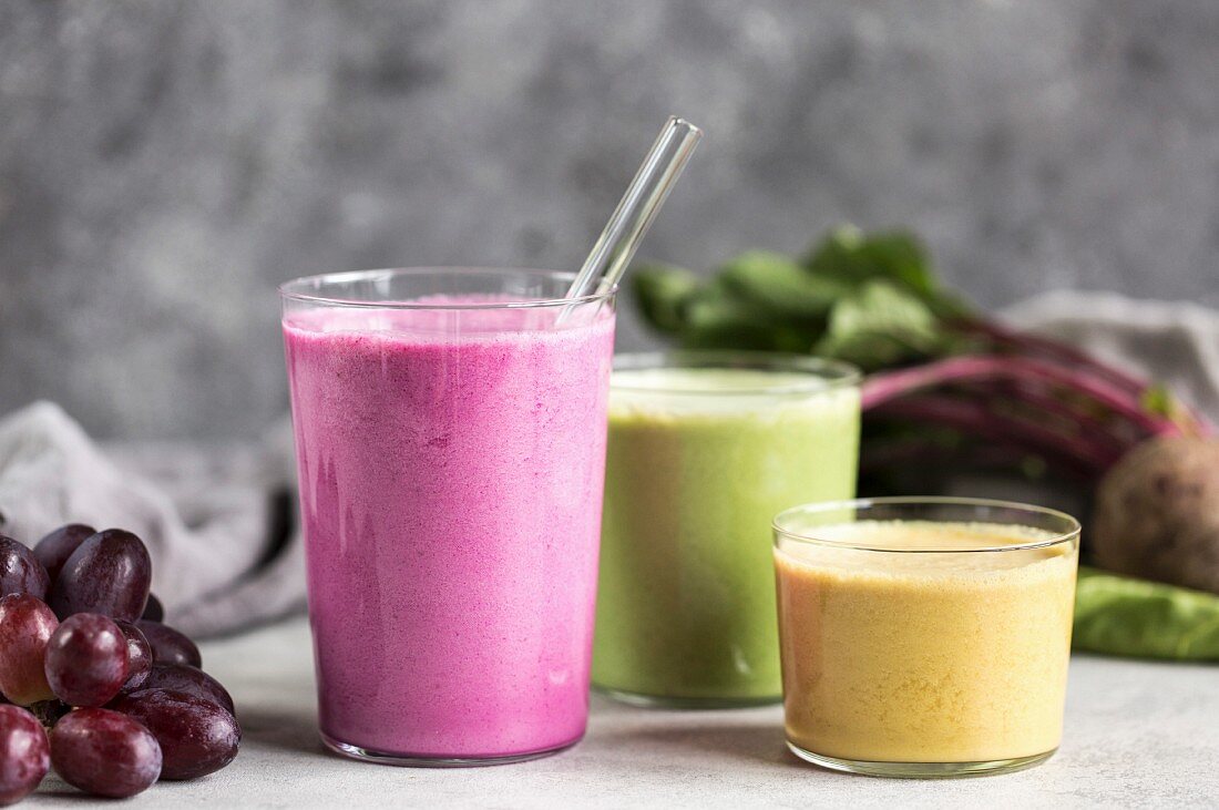 Three glasses containing colourful vegetable smoothies