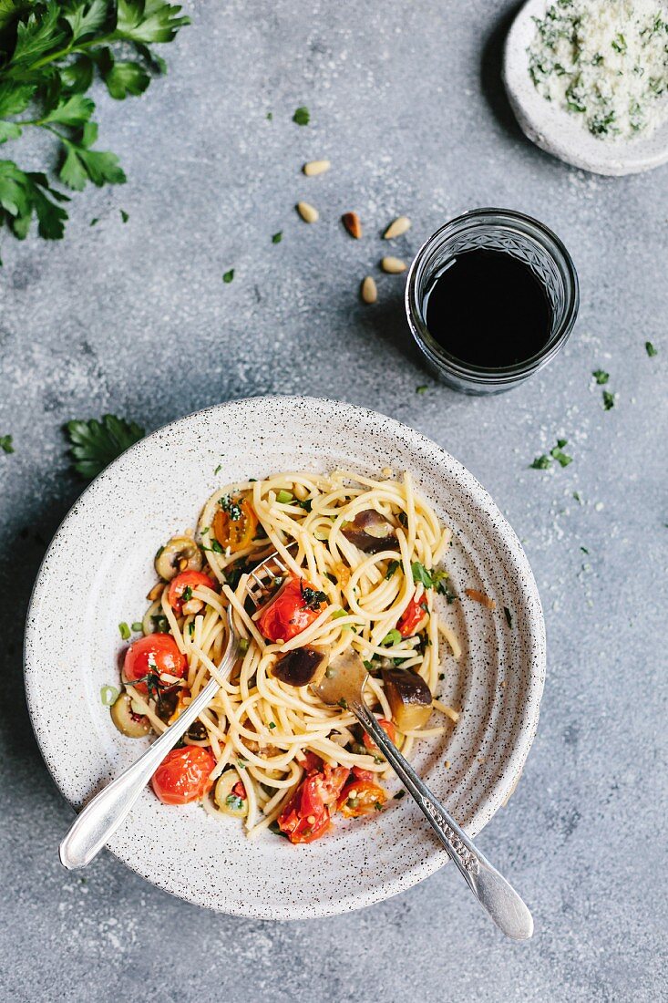 A half-eaten bowl of spaghetti with aubergine and tomatoes