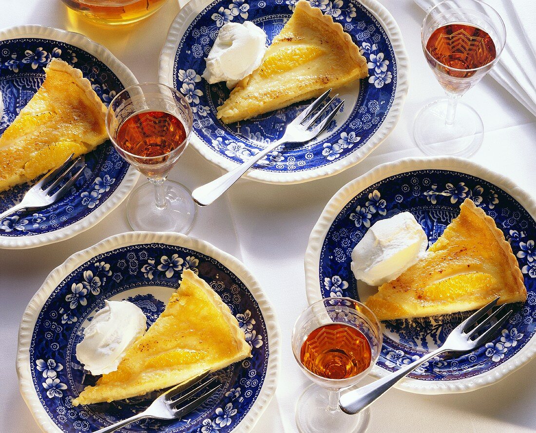 Four pieces of orange tart with cream on plates