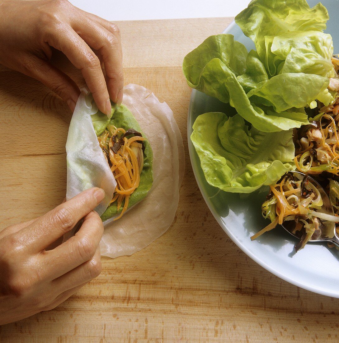 Making spring rolls: filling rice paper with vegetables