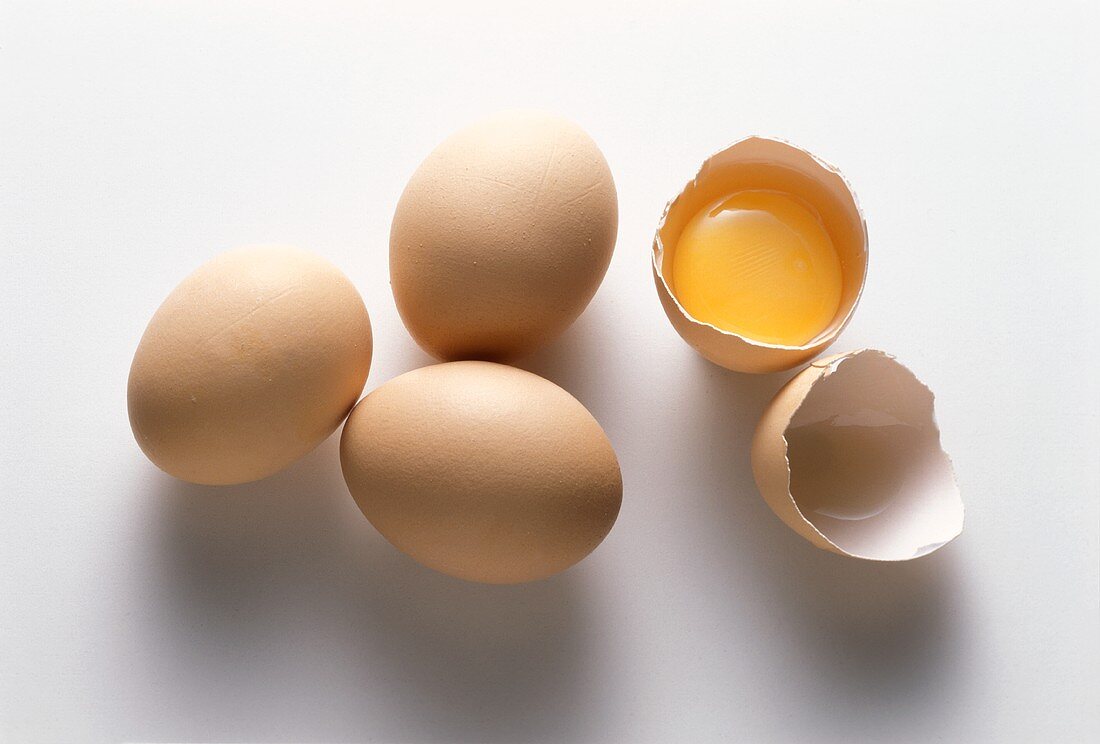 Vier braune Eier, eines davon aufgeschlagen