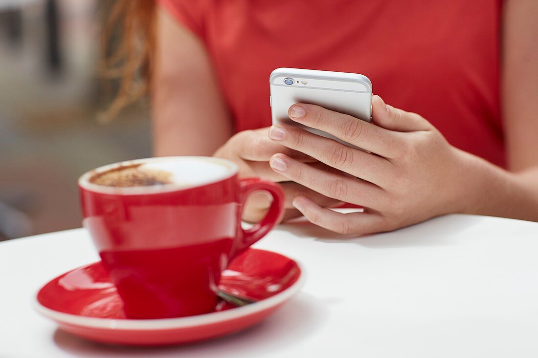 Woman using smartphone with coffee