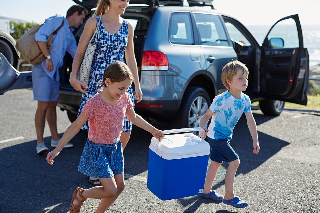 Family carrying picnic cold box