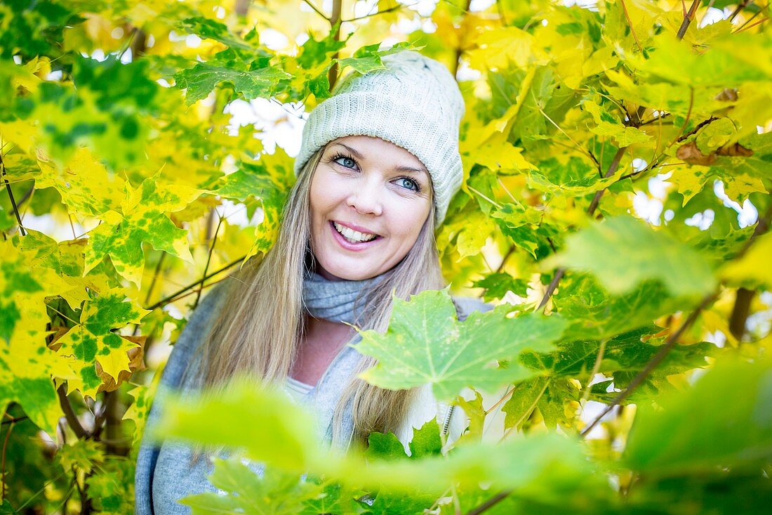 Young woman surrounded by autumn leaves