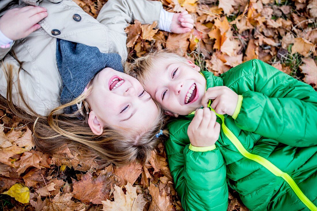 Children lying on dried leaves