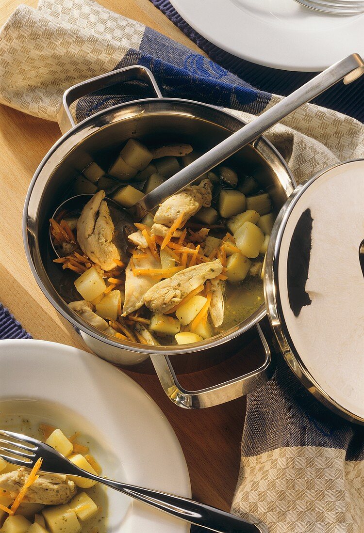 Kartoffeleintopf mit Huhn im Topf mit Kelle & auf Teller