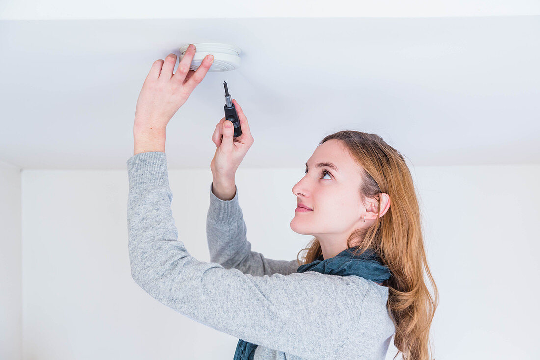 Woman installing a smoke detector