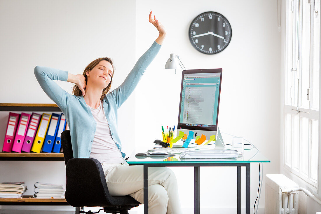 Office woman stretching arms at work