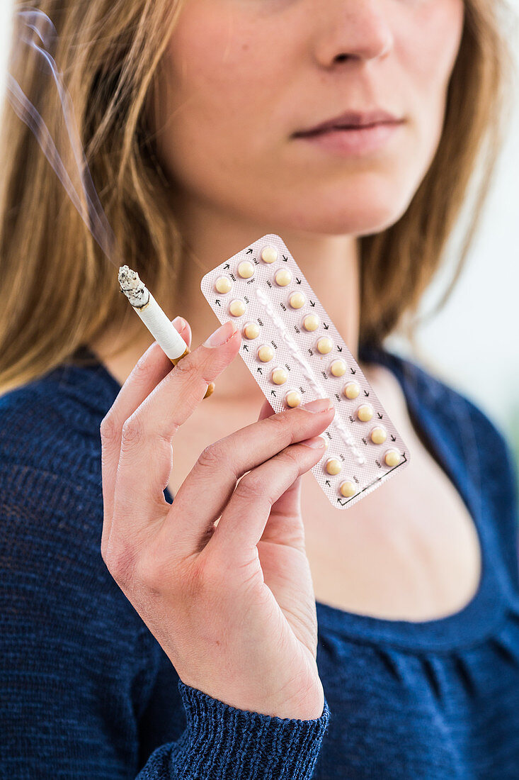 Woman holding contraceptive pills and cigarette