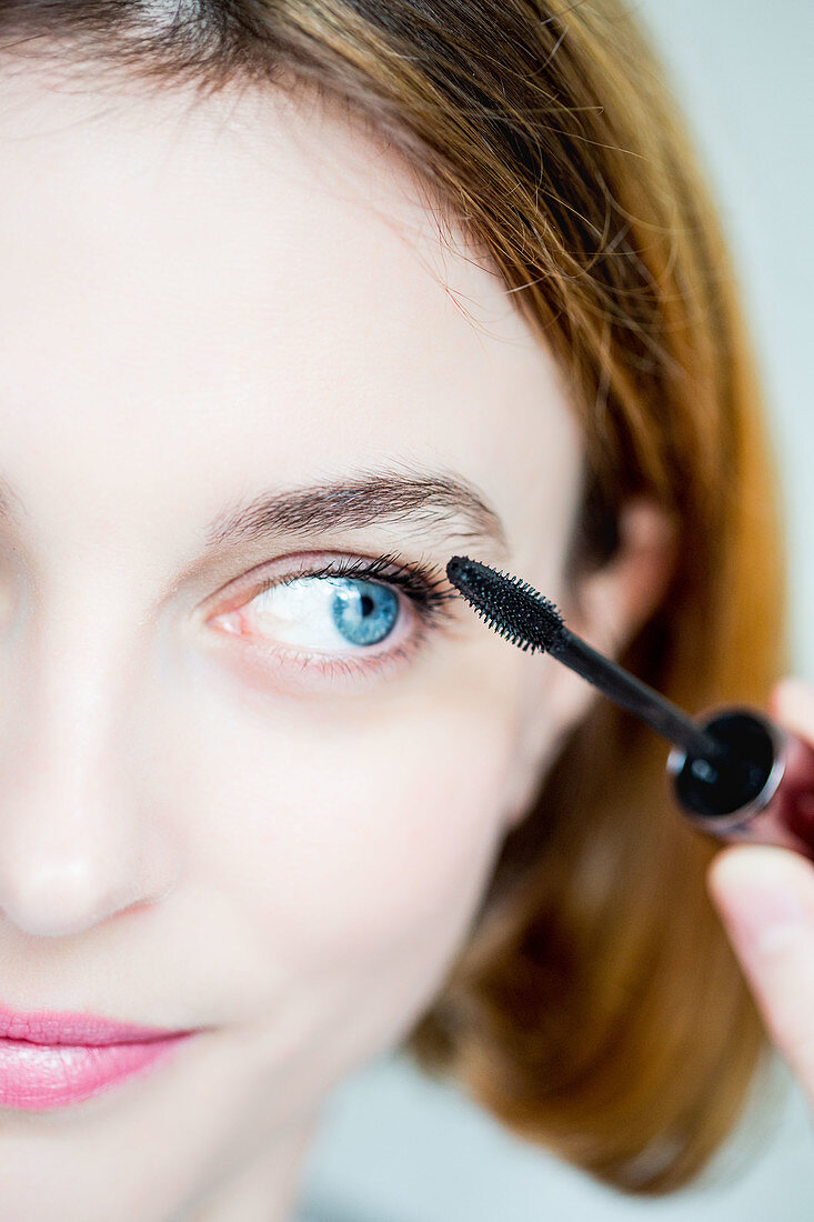 Woman applying mascara on her eyelashes