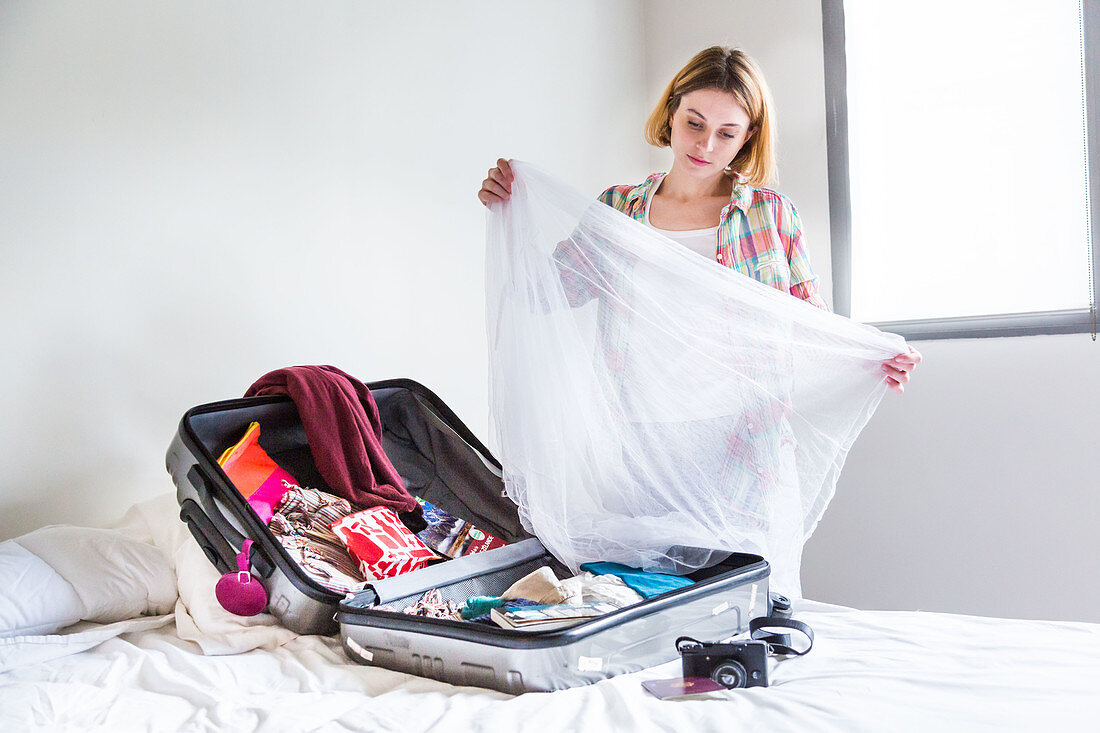Woman putting a net in her suitcase