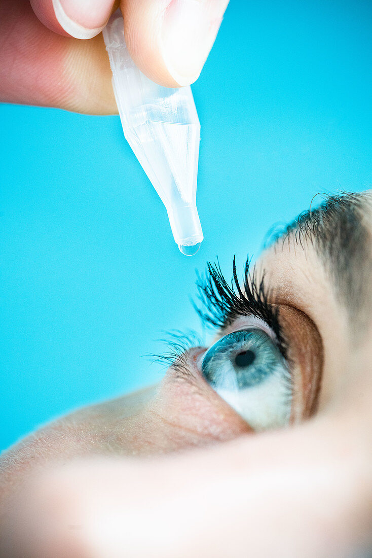 Woman applying eye-drops into her eye