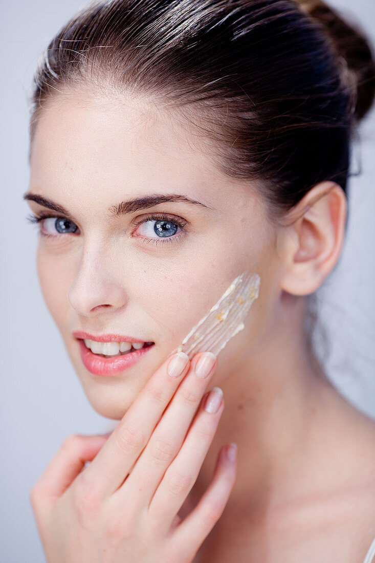 Woman exfoliating her face with facial scrub treatment