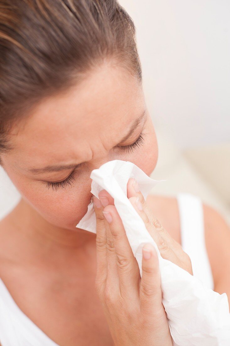 Woman blowing nose on tissue