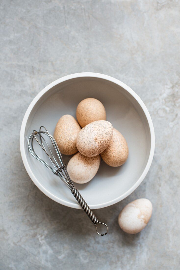 Frische Eier in Schüssel mit Schneebesen