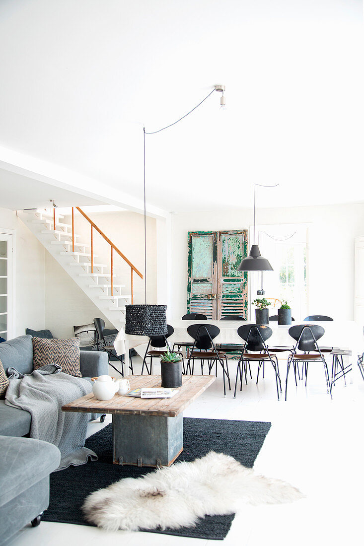 Grey sofa in front of dining table and chairs in open-plan interior