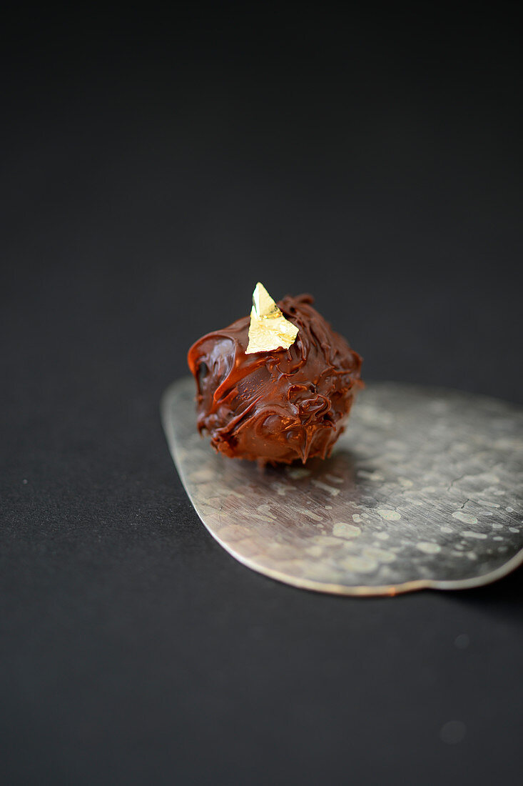 A chocolate truffle decorated with gold leaf