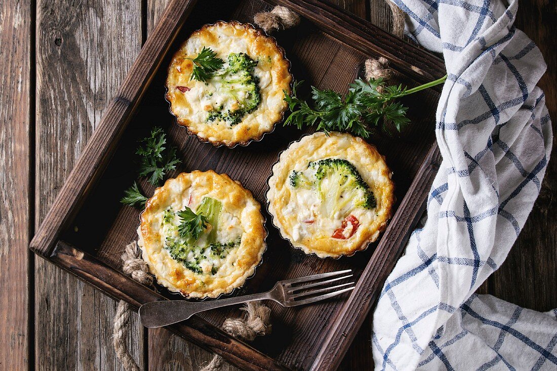 Baked homemade quiche pie in mini metal forms served with fresh greens