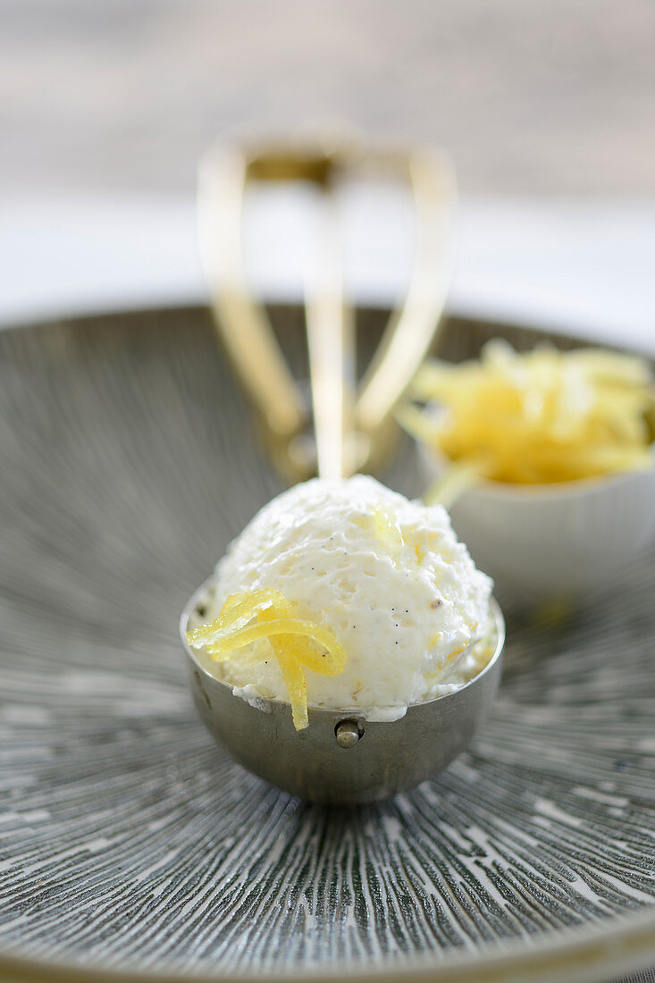 Vanilla ice cream with candied lemon zest in an ice cream scoop