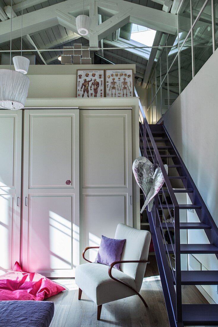 Cupboard with panelled doors next to purple staircase leading to attic