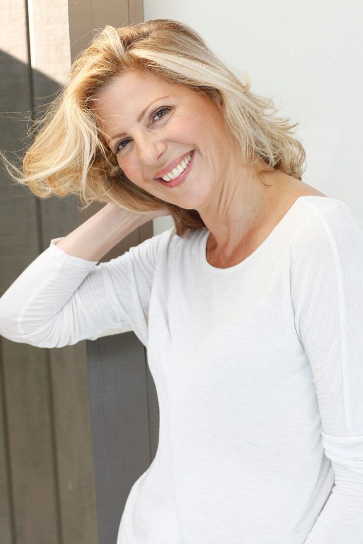 A blonde woman wearing a white long-sleeved top