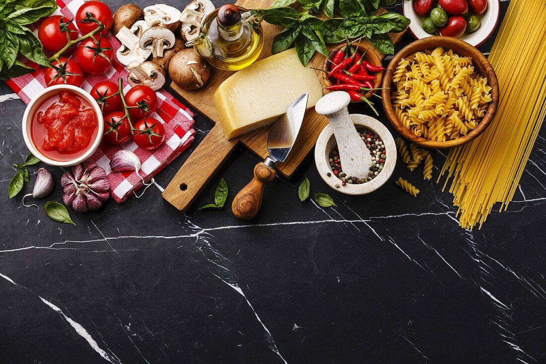 Italian food ingredients with Olives, pasta Spaghetti, Oil, Parmesan cheese, Brown mushroom, Tomato, Garlic, Basil, Chilli pepper and spices