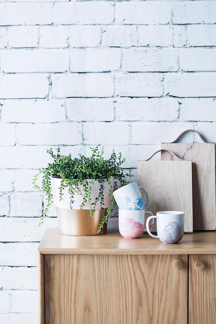 DIY marbled cups next to houseplant on sideboard