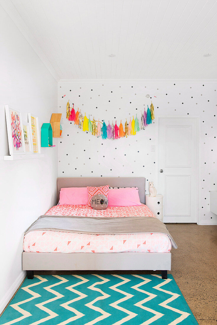 Tassel garland over the bed against a dotted wall
