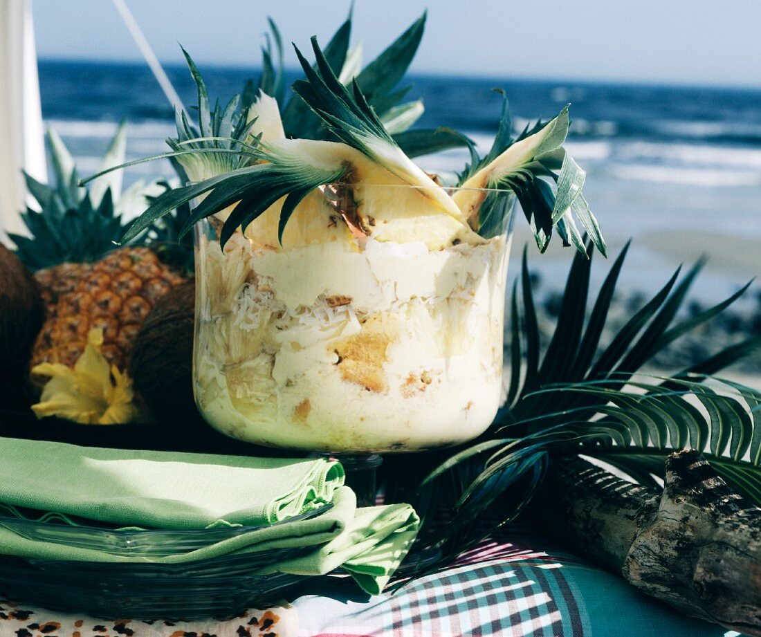 Caribbean pineapple trifle in shell on table on the beach