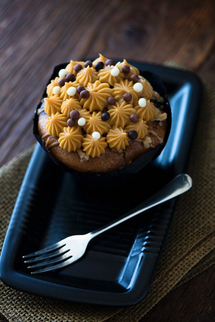 A salted caramel cupcake on a black plate with a fork