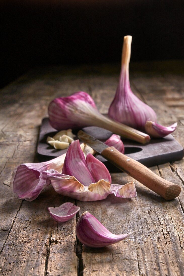 Fresh garlic on a wooden board with a peeler