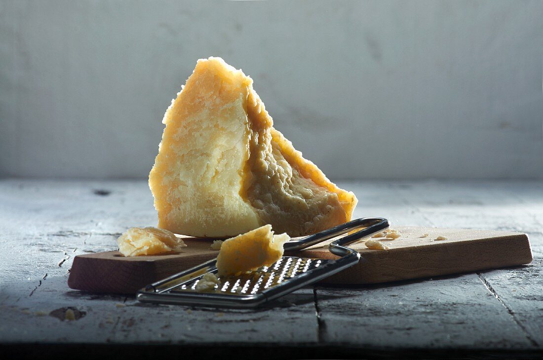 Grana Padano auf Holzbrett mit Käsereibe