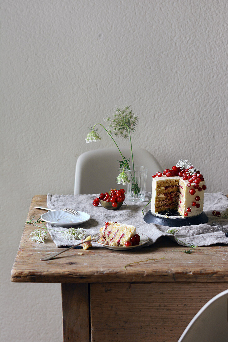 A redcurrant and elderflower cake on a wooden table