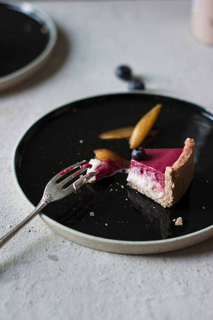 Ein Stück rohe Pflaumen-Vanille-Tarte mit Heidelbeeren