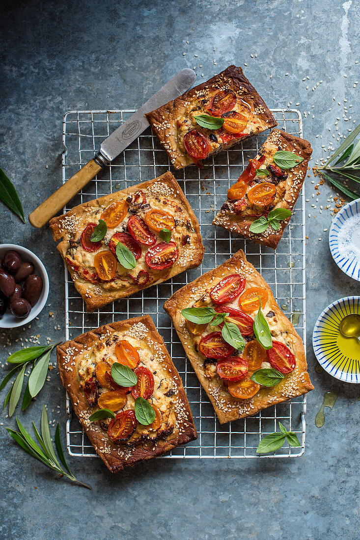 Mürbteigtartes mit Tomaten, Feta, Oliven, Sesam und frischem Basilikum