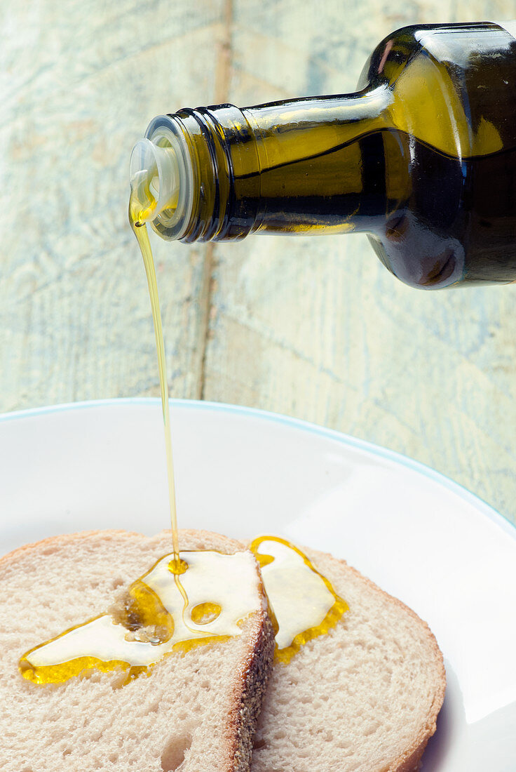 hands pouring olive oil onto bread