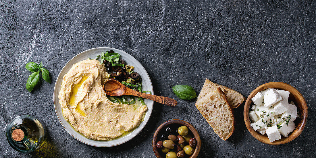 Hummus serviert mit Oliven, Brot und Feta (Aufsicht)