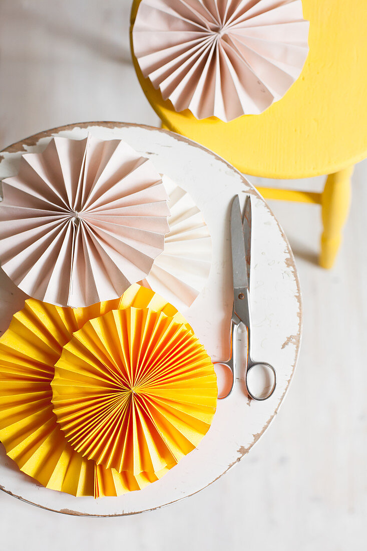 Pink and yellow paper rosettes on two stools