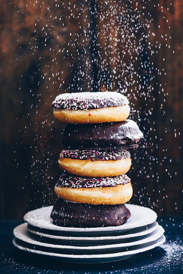 Doughnuts being sprinkled with icing sugar