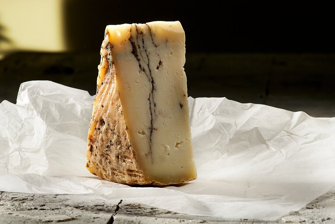 A wedge of pecorino with truffle on white paper