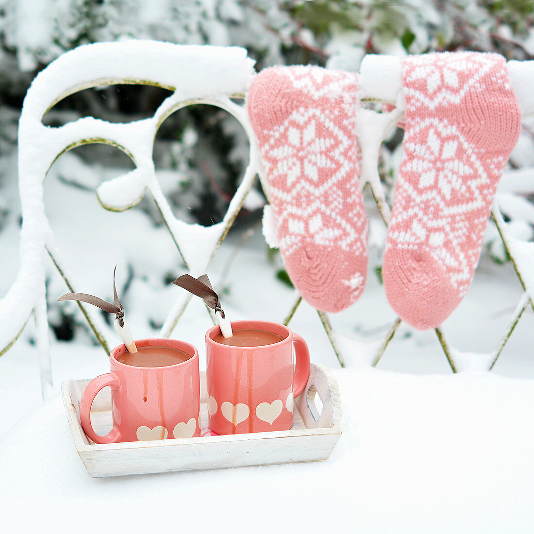 Two cups of hot chocolate on a snow-covered garden bench