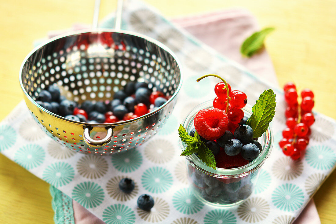 Frische Sommerfrüchte in Glas und Metallsieb