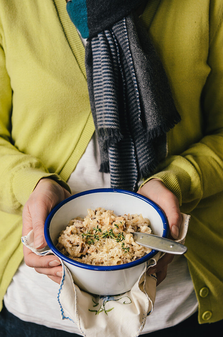 Frau hält eine Schüssel Risotto mit Thymian und Parmesan