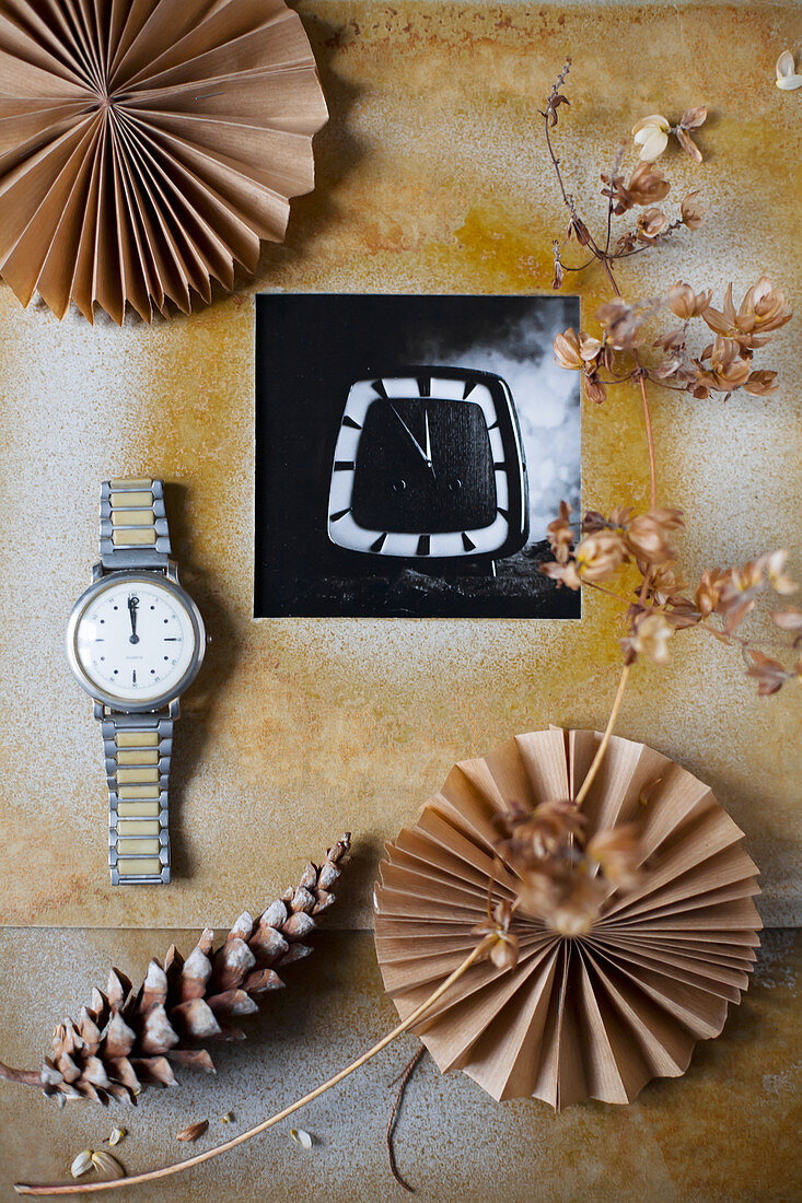 Black-and-white photo in hand-made frame, dried flowers, wristwatch, pine cone and paper rosettes
