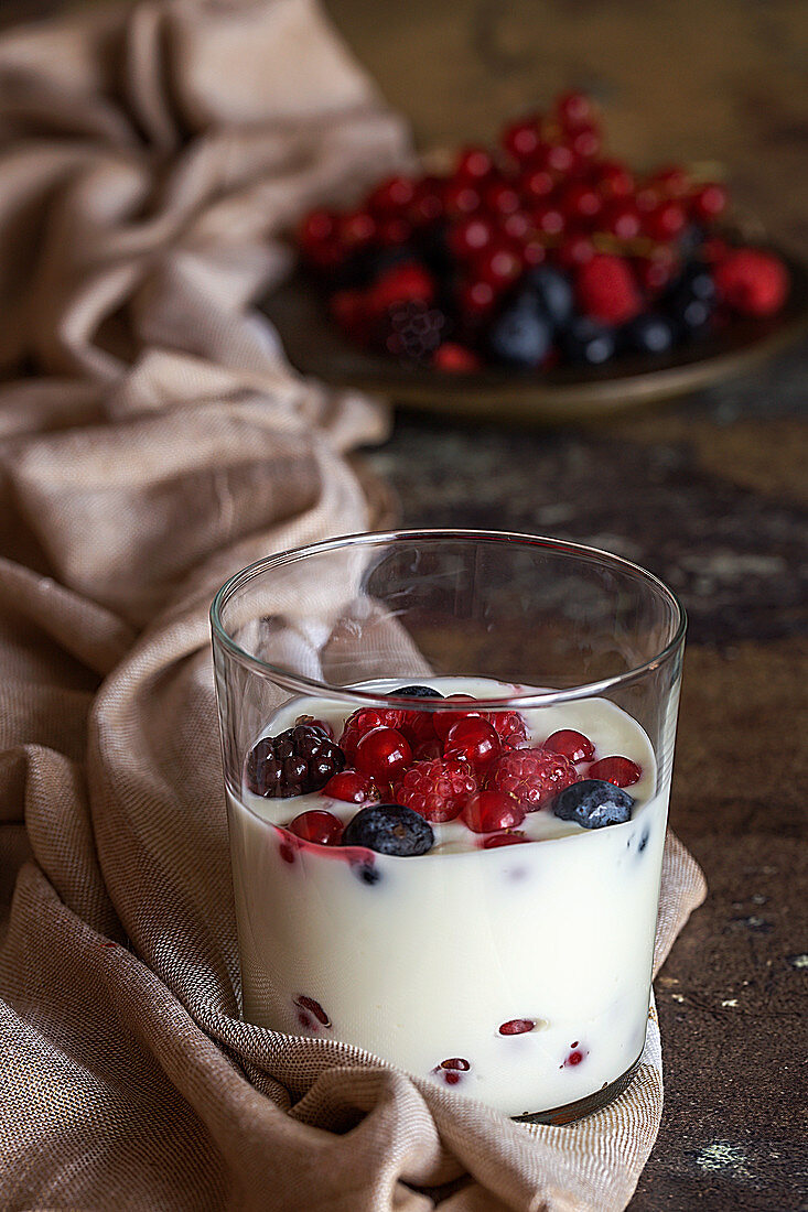 Yoghurt with berries in a glass on a wooden table