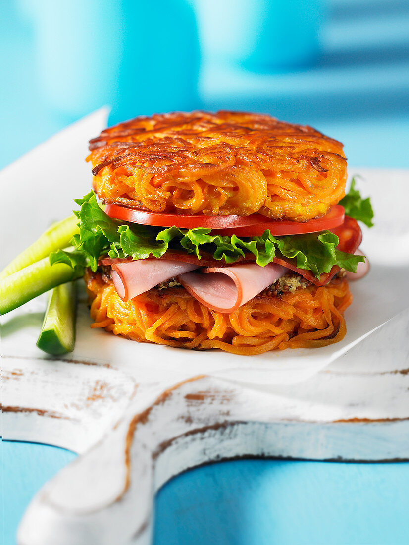 A ham, salad and tomato sandwich made with a spiralized sweet potato bun