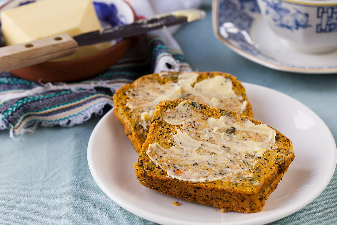 Two buttered slices of sweet potato bread with seeds and raisins