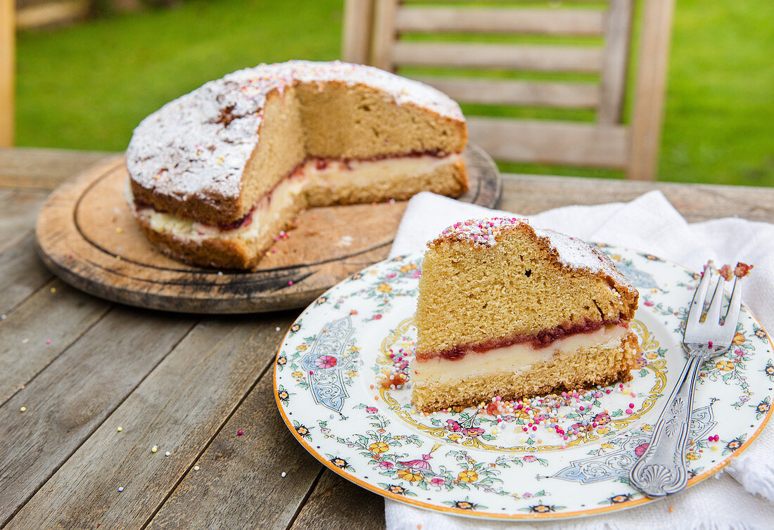 Victoria Sponge Cake mit Marmelade, Buttercreme, Puderzucker und bunten Zuckerperlen