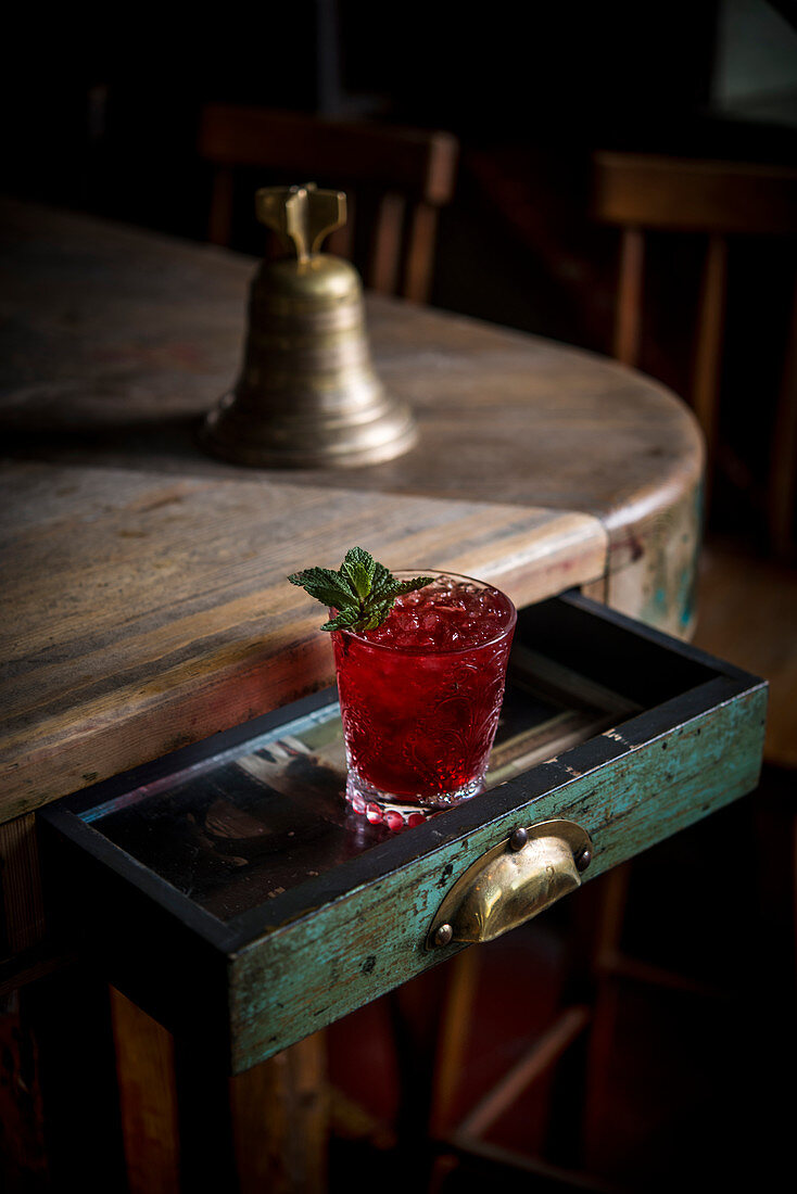 Roter Cocktail mit Eiswürfeln und Minzblättechen