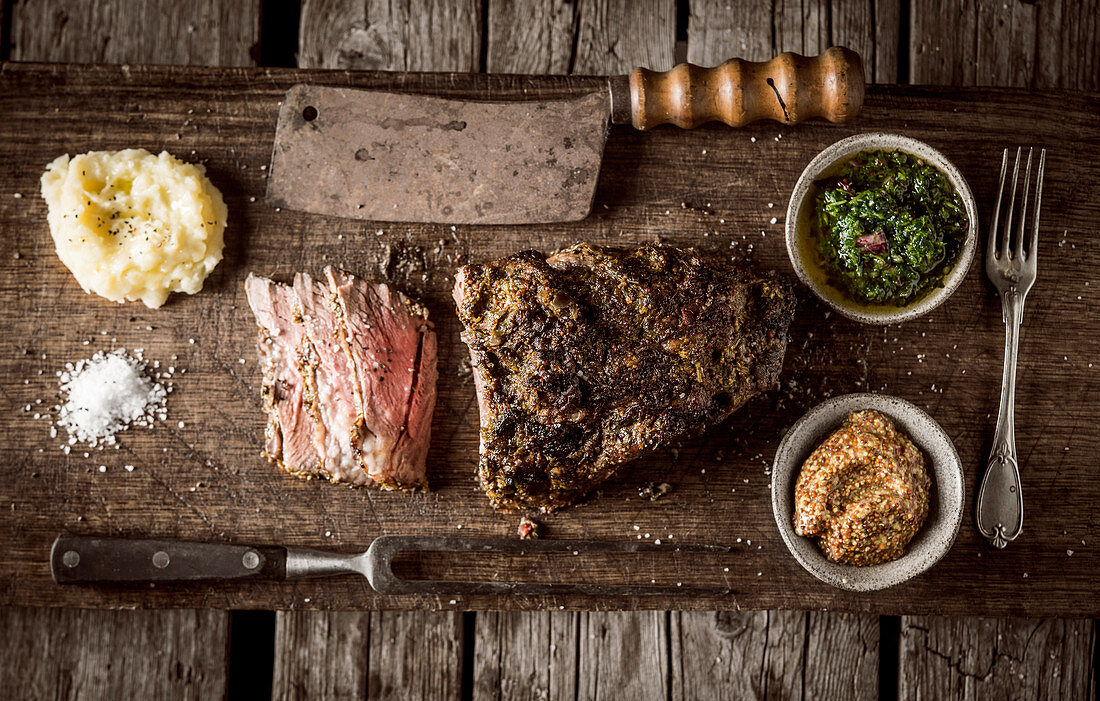 Roast beef with side dishes on a rustic wooden board